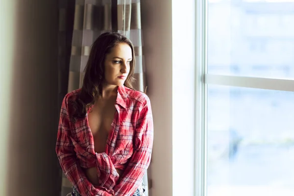 Young caucasian woman in plaid shirt and denim shorts poses in natural light