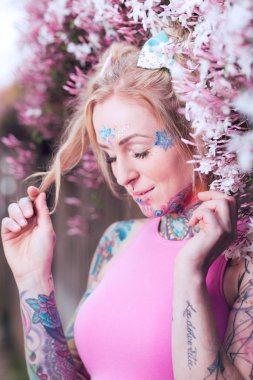 Sıkı sarışın beyaz kadın pembe çiçekler yakınındaki dövmeli portresi