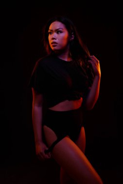 Turuncu ve mavi renkli ışıklar altında siyah karşı uygun Genç Asyalı kadın siyah tek parça pozlar