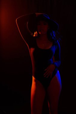 Turuncu ve mavi renkli ışıklar altında siyah karşı uygun Genç Asyalı kadın siyah tek parça ve kolye pozlar