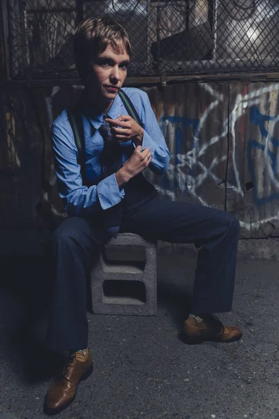 Queer woman dressed in suit and tie poses in a grungy industrial location