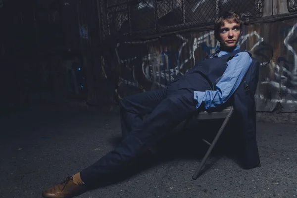 Queer woman dressed in suit and tie poses in a grungy industrial location