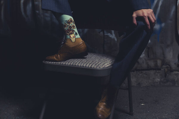 Queer woman dressed in suit and tie poses in a grungy industrial location