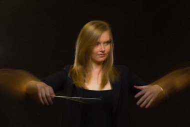 Genç kafkas kadın orkestra şefi baton ile jestleri ve hafif iz bırakır