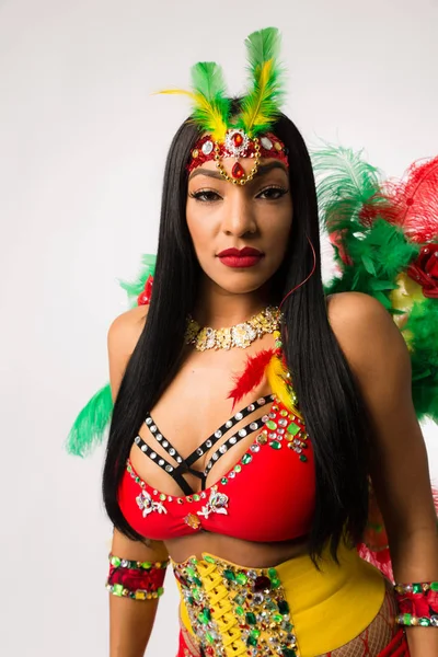 Fit young dark haired mixed race woman in Carnaval costume and athletic shoes posing on clean white background