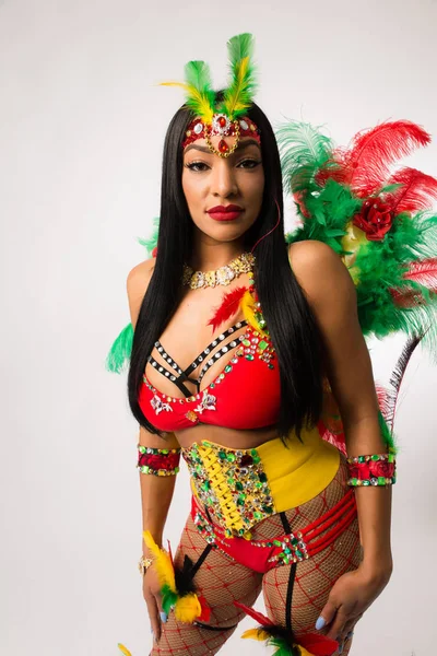 Fit young dark haired mixed race woman in Carnaval costume and athletic shoes posing on clean white background