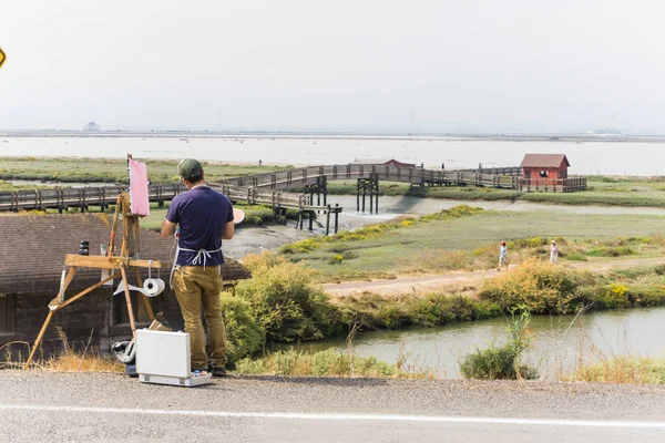 Man paints in plein-air watercolor in a wetland marsh