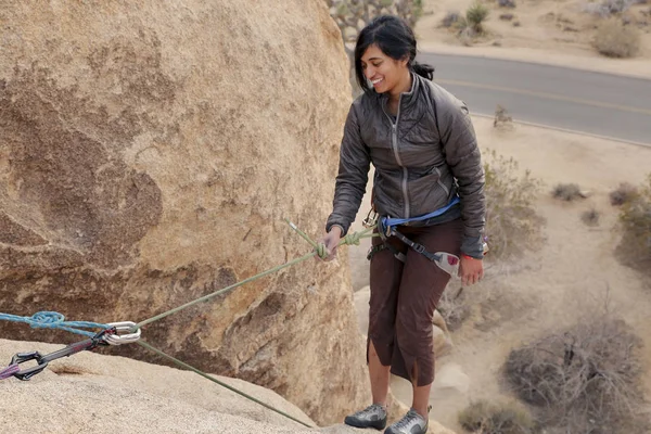 Southeast asian woman rock climbs in the California desert