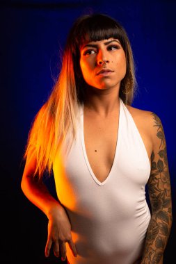 Patlama ve renkli saç ile alternatif model beyaz bir mayo giyen mavi ve turuncu ışık altında pozlar