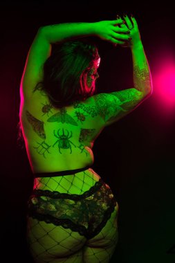 Yeşil ve pembe aydınlatma altında renkli saç ve kürk ceket ve fishnets ile curvy alternatif model