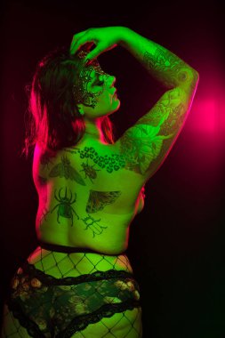 Yeşil ve pembe aydınlatma altında renkli saç ve kürk ceket ve fishnets ile curvy alternatif model