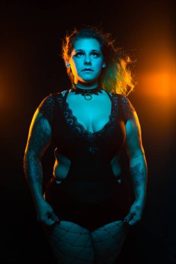 Mavi ve turuncu Aydınlatma altında renkli saç ve dantel bodysuit ve fishnets ile kıvrımlı alternatif model yakın portre