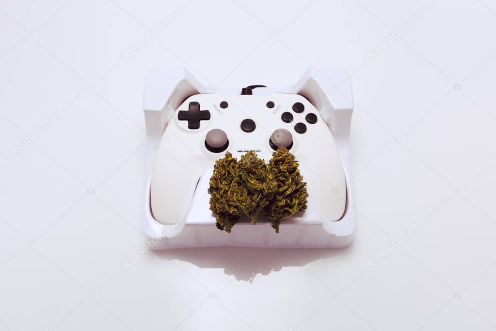 Cannabis flower and game controller on white background