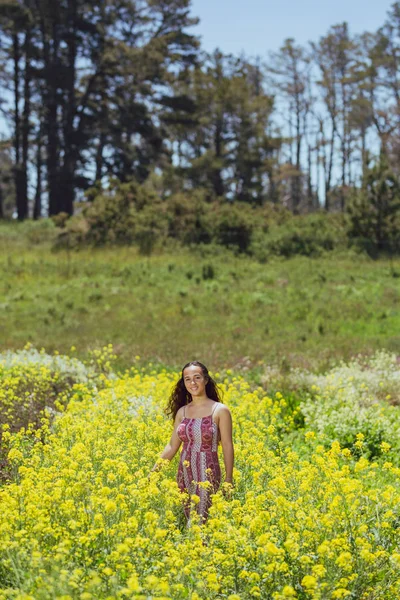 Молодая женщина смешанной расы стоит на цветочном поле на ферме — стоковое фото