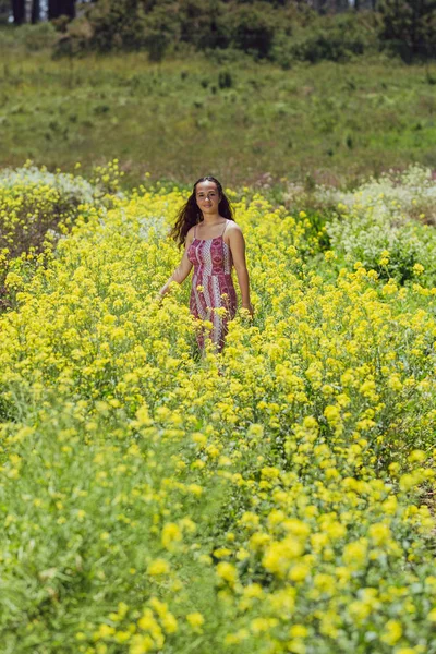 Молодая женщина смешанной расы стоит на цветочном поле на ферме — стоковое фото