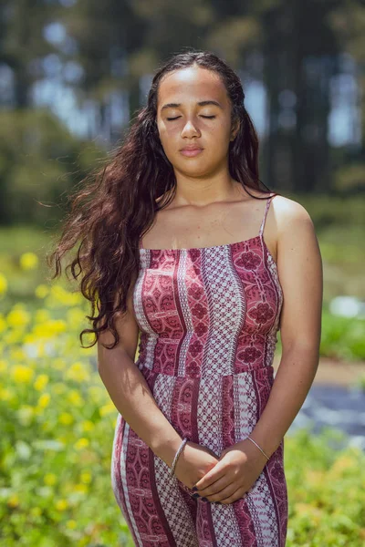 Mixed race young woman stands in a flower field on a farm