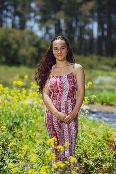 Mixed race young woman stands in a flower field on a farm