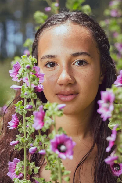 Mezcla de raza joven mujer de pie entre las flores altas fuera — Foto de Stock
