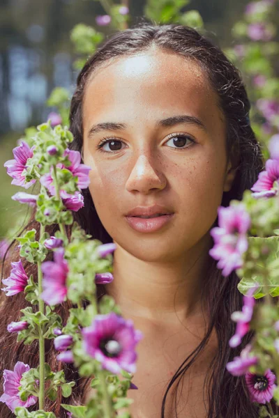 Mezcla de raza joven mujer de pie entre las flores altas fuera — Foto de Stock
