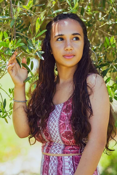 Karışık ırk genç kadın bir çiftlikte bir zeytin ağacının altında duruyor — Stok fotoğraf