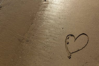 Mendocino sahili boyunca kumda el çizilmiş kalp