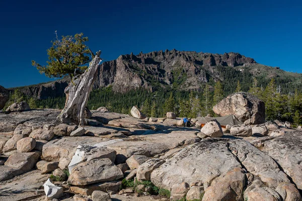 Granit kayalar ve ağaç s arasında eğimli küçük sırt çantası çadırı