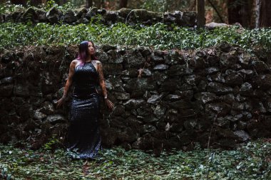 Siyah gece elbisesi giymiş Asyalı kadın terk edilmiş bir yerde poz veriyor.