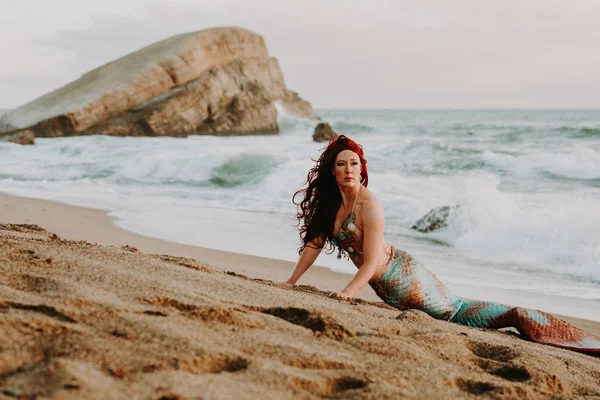 Caucasian redhead woman with mermaid tail reclines on the beach — Stock Photo, Image