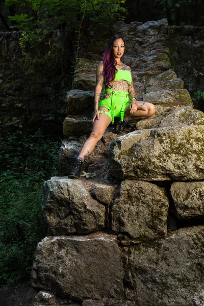 Asiatische tätowierte Frau in Neon Rave Kleidung posiert auf einem verlassenen — Stockfoto