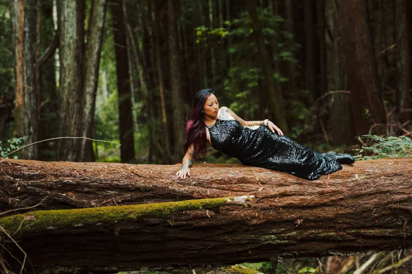Siyah gece elbisesi giymiş Asyalı dövmeli bir kadın düşmüş bir yerde poz veriyor. — Stok fotoğraf