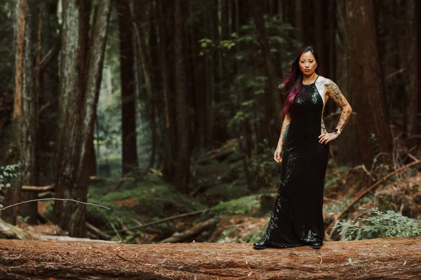 Asiático tatuado mujer en negro vestido de noche poses en un caído re — Foto de Stock