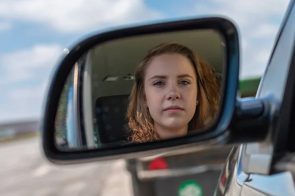 Женщина в машине смотрит в зеркало заднего вида — стоковое фото