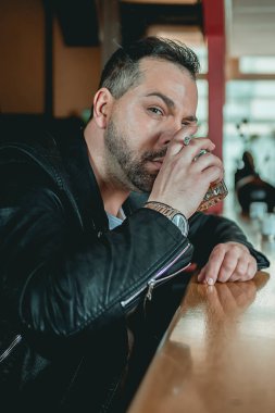 Elinde kaşı ve viskisi olan bir barda adam