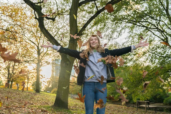 Young woman throws leaves in a park