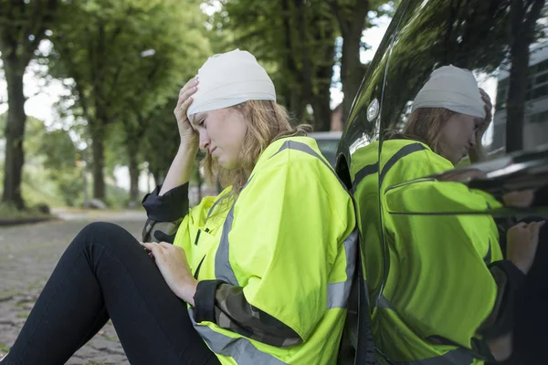 Una mujer joven con lesión en la cabeza se apoya contra un coche — Foto de Stock