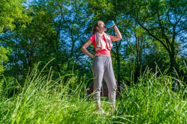 doğada bir koşucu mavi bir su şişesi içecekler