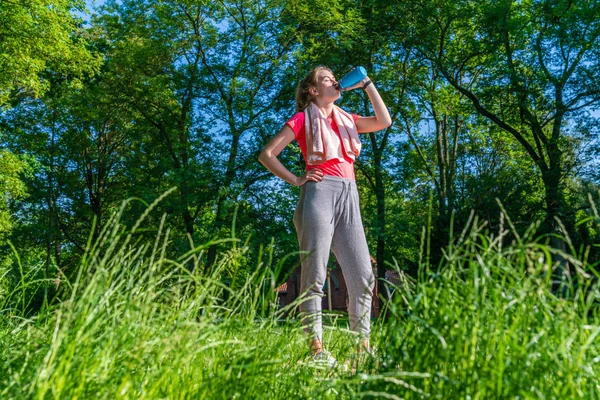 doğada bir koşucu mavi bir su şişesi içecekler