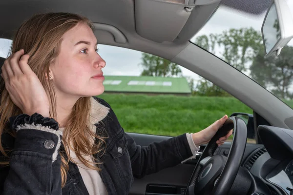 Woman is distracted while driving a car and makes herself the hair — 스톡 사진