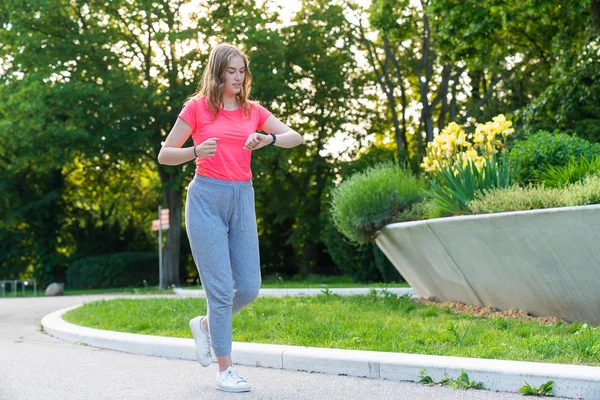 一个女人在公园里跑步，检查她的健身手表上的脉搏 — 图库照片