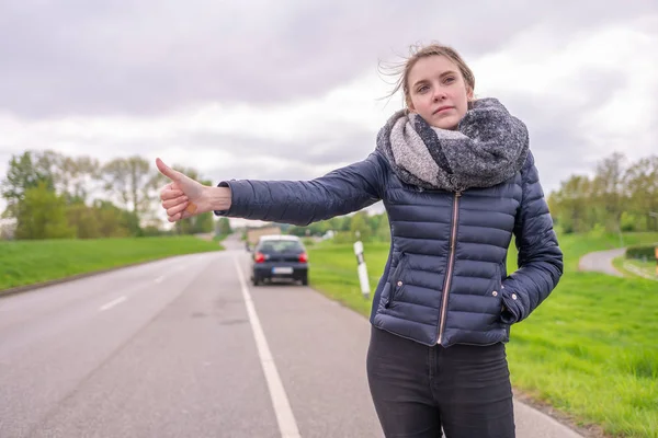Junge Frau mit Autopanne will trampen — Stockfoto
