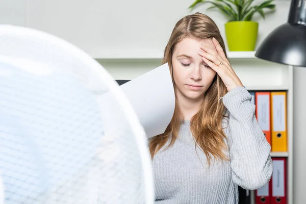 Žena v kanceláři trpí teplem a používá ventilátor k chlazení — Stock fotografie
