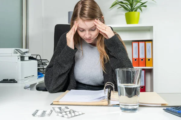 Žena v kanceláři s bolestí hlavy na stole — Stock fotografie