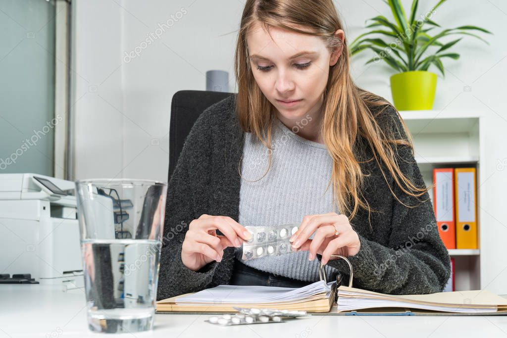 woman in the office takes pills against her headache