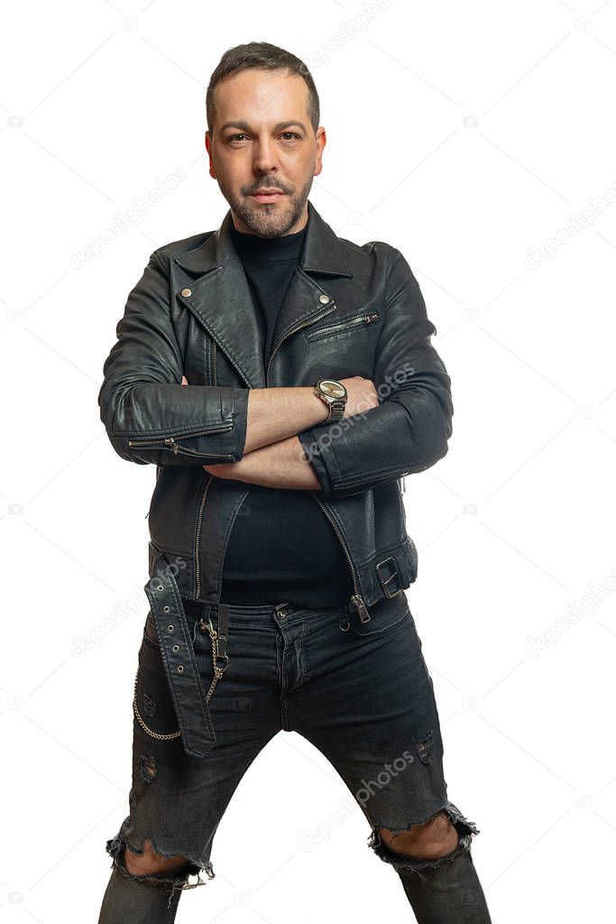 A man in black leather jacket with crossed arms looks into the camera