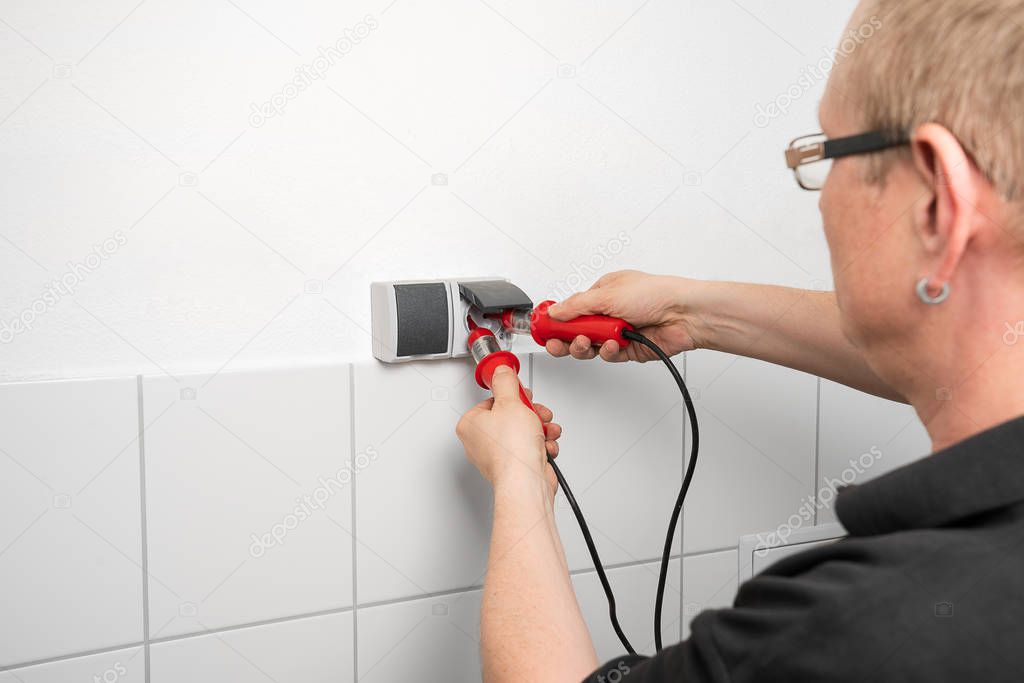 Electrician checks a socket with a voltage indicator