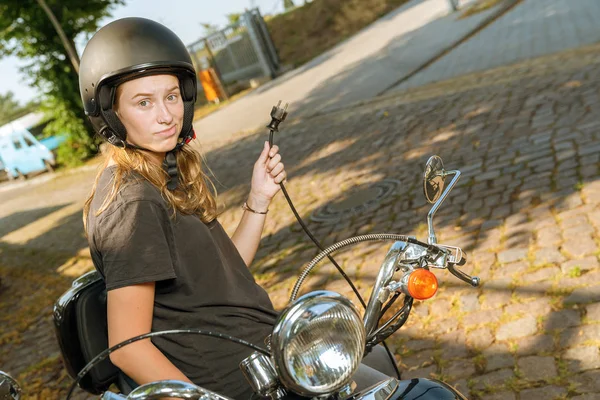 Молодая женщина с электрическим скутером ищет розетку для зарядки — стоковое фото