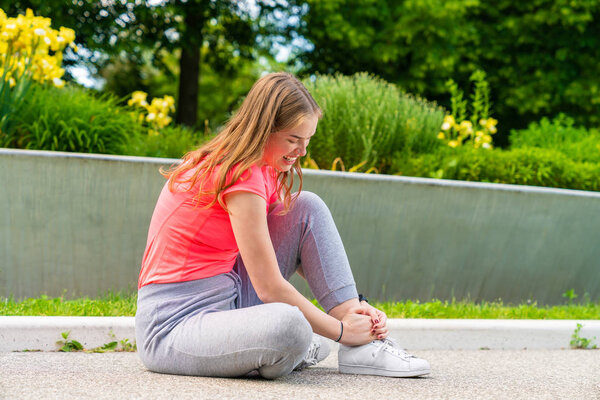 a woman had an sport accident with her ankle and holds it tight