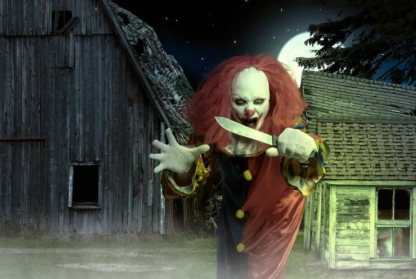 An eerie clown with a knife in hand in front of a scary scene — Stock Photo, Image