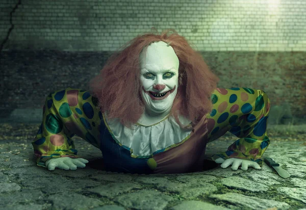 Ein grinsender Killer-Clown steigt aus der Kanalisation auf — Stockfoto