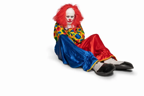 Ein trauriger Clown, der isoliert auf dem Boden sitzt — Stockfoto